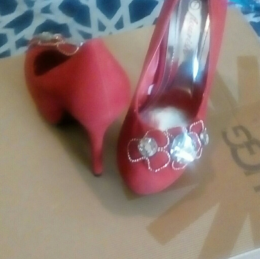 Red high heels with jewelry on them.